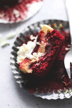 a piece of red velvet cake sitting on top of a paper plate next to a fork