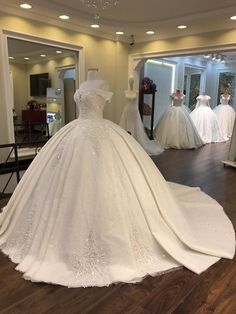 a white wedding dress on display in a room with mannequins and other dresses