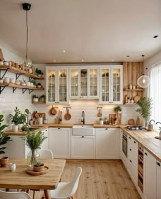 a kitchen filled with lots of wooden counter tops and white cupboards next to a dining room table