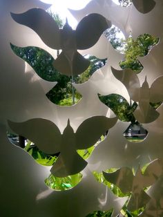 an artistic sculpture made out of white paper with leaves hanging from it's sides