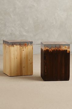 two wooden stools sitting next to each other on top of a white floor covered in dirt