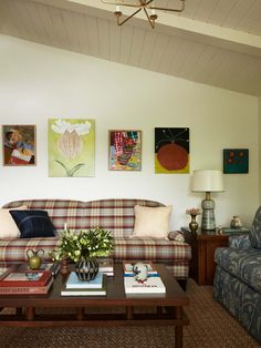 a living room filled with furniture and paintings on the wall above it's coffee table