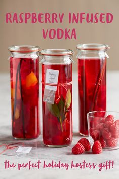 three jars filled with raspberry tea on top of a white counter next to some strawberries