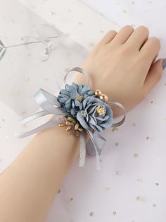 a woman's hand wearing a blue and silver flower bracelet with pearls on it