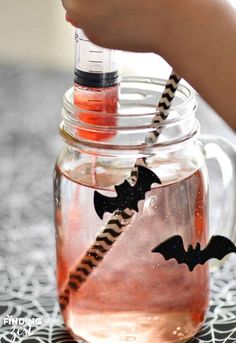 a person is holding a straw in a jar filled with liquid and bats on it