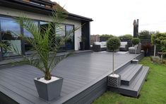 a deck with potted plants on it in front of a house