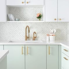 a kitchen with white cabinets and gold pulls on the cabinet doors is seen in this image