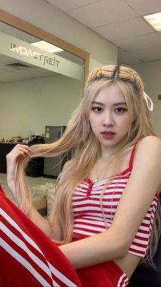 a woman with long blonde hair sitting in front of a mirror holding an american flag