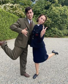 a man and woman dressed in business attire posing for the camera with their hands up