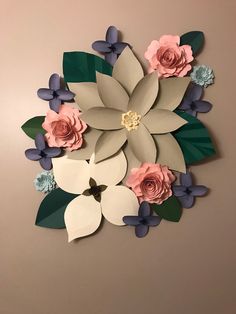 paper flowers are arranged on the wall with green leaves and pink roses in the center