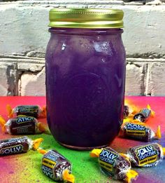 a jar filled with purple liquid surrounded by candy