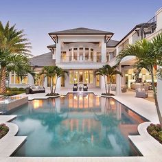 a large house with a pool in front of it and palm trees around the pool