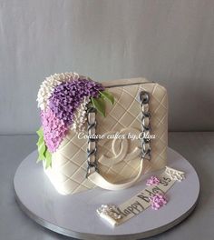 a cake that is shaped like a purse and has flowers on the front, along with a name tag