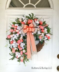 a wreath with pink and white flowers is hanging on the front door's side