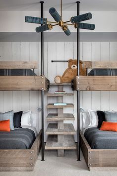 two bunk beds in a room with wooden floors and white walls, one has a teddy bear hanging from the ceiling