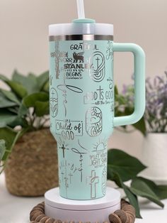 a blue travel mug sitting on top of a white table next to some plants and nuts