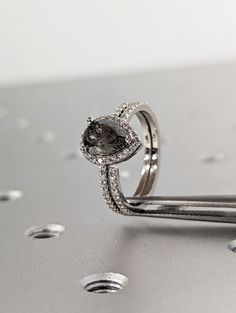 a diamond ring sitting on top of a silver surface with drops of water around it