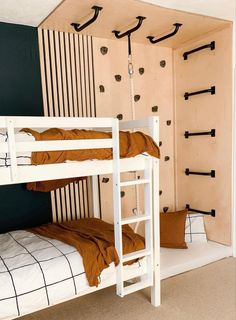 two bunk beds in a small room with ladders on the wall and pillows on the floor