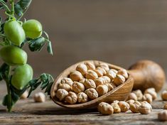 a wooden spoon filled with nuts next to some green apples