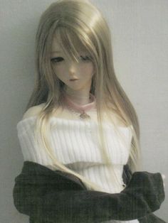 a doll with long blonde hair wearing a sweater