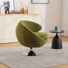 a green chair sitting on top of a wooden floor next to a black and white table