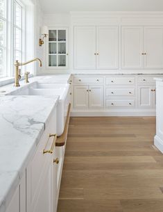 a large kitchen with white cabinets and marble counter tops, along with wooden flooring