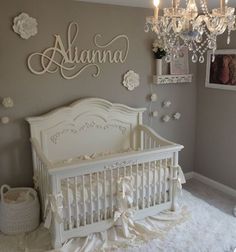 a baby's room with a crib, chandelier and pictures on the wall