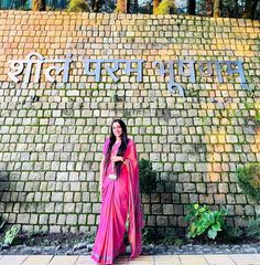 a woman standing in front of a brick wall with the word india written on it