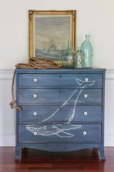 a blue dresser with an image of a boat painted on the front and bottom drawers