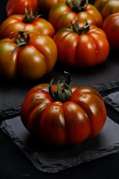 several tomatoes are sitting on top of slates