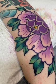 a woman's arm with flowers and leaves on it