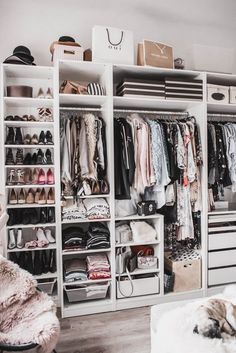 an organized closet with clothes, shoes and other items on shelves next to a bed