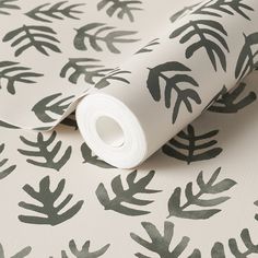 a white and green wallpaper with black leaves on the back ground, in front of an off - white background