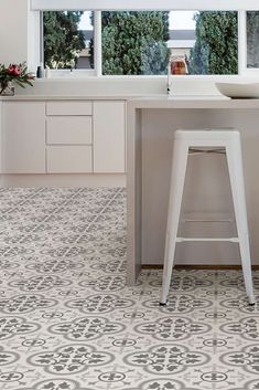 a kitchen with white cabinets and counter tops, two stools in front of the window