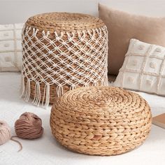 woven baskets and balls of yarn sit on a white tablecloth next to decorative pillows