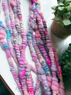 several strands of dyed wool sitting on top of a white table next to a potted plant