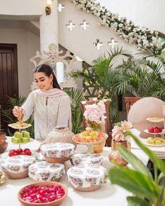 a woman standing in front of a table filled with plates and bowls full of food