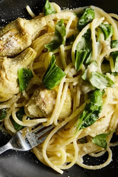 a plate of pasta with chicken, spinach and parmesan cheese