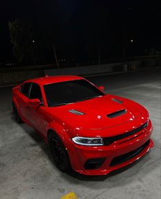 a red car parked in a parking lot at night