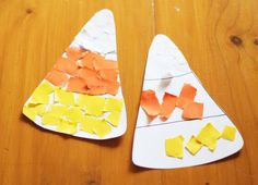 two paper plates with cut out pieces of orange and yellow paper on them sitting on a wooden table