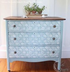 an old dresser painted in blue and white with flowers on top