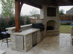 an outdoor kitchen with grill and seating area