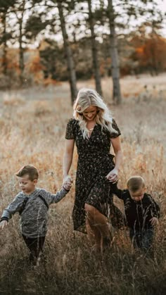 a woman and two boys are playing in the tall grass with their hands on each other