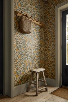 a wooden stool sitting in front of a wall with a deer's head on it