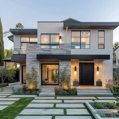 a modern house with grass and plants in the front yard