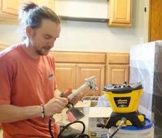 a man is working on an electrical device in his kitchen with the help of a hand held drill