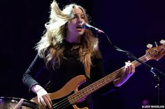 a woman with long blonde hair playing a bass