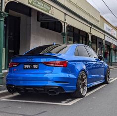 the blue car is parked on the side of the road in front of a building