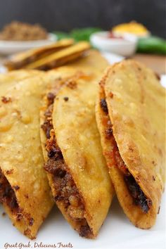 three tortillas sitting on top of a white plate next to some dipping sauce