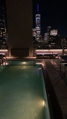 an outdoor swimming pool with city lights in the background